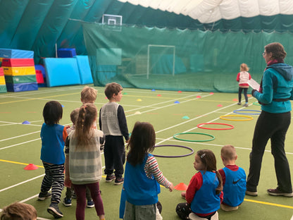 Enfants et coach HOLICAMP devant une structure gonflable lors d'une animation en salle